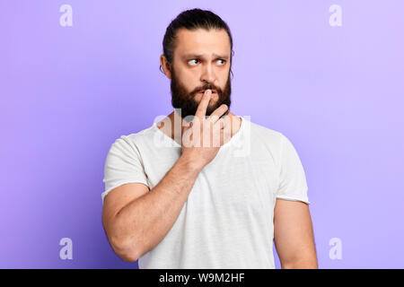 Porträt der jungen nachdenklich nachdenklich Mann mit Angst und Sorge Ausdruck, beißt finger Nägel, trägt weiße T-Shirt, Angst, Arzt. Stockfoto