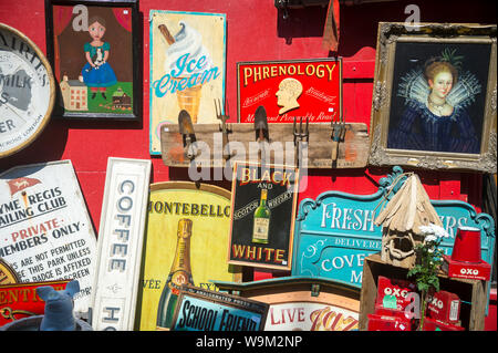 LONDON - 20. APRIL 2019: Altmodische Zeichen dekorieren eine helle rote Wand an der wöchentlichen Antiquitätenmarkt auf der Portobello Road in Notting Hill. Stockfoto