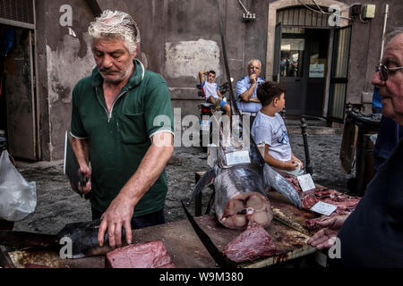 Fischhändler Vorbereitung ein Stück Fisch für einen Client im La Pescheria. Catania, Sizilien, Italien Stockfoto