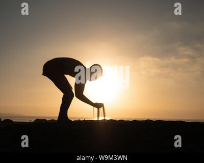 Männliche herauf Sand am Strand gegen den Sonnenaufgang. Der Strand von Maspalomas, Gran Canaria Stockfoto