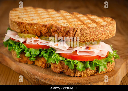 Handgefertigte Türkei Sandwich mit Tomate, Salat und Gurken, auf hölzernen Hintergrund, selektiver Fokus Stockfoto