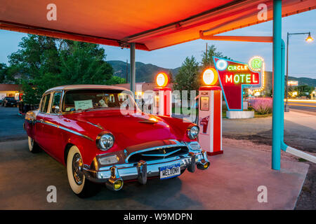 Dämmerung Blick auf 1955 Studebaker President classic car Vor antiken gas Pumpen elektrische Auto Ladegeräte konvertiert geparkt; den Kreis R Motel; Salida Stockfoto