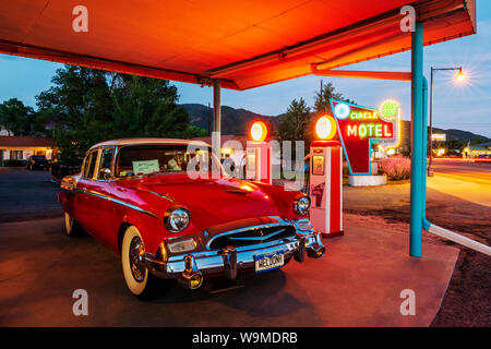 Dämmerung Blick auf 1955 Studebaker President classic car Vor antiken gas Pumpen elektrische Auto Ladegeräte konvertiert geparkt; den Kreis R Motel; Salida Stockfoto