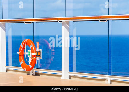 Orange Rettungsring auf einem Deck von Kreuzfahrtschiff mit Ozean auf Hintergrund mit Kopie Raum Stockfoto