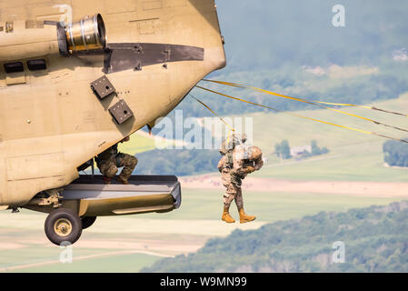 Soldat Sprung aus einem Chinook bei 2019 Leapfest, einer internationalen statische Linie Fallschirm Training und Wettbewerb, bewirtet durch RI Natl. Guard. Stockfoto