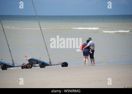 Arm-in-Arm, ein Ehepaar mittleren Alters mit Blick zum Meer in La Manche, oder den Englischen Kanal von einem Strand in Frankreich Stockfoto