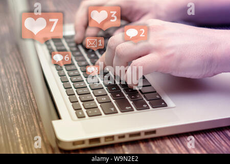 Person ist mit Laptop mit schwarzen Tasten, Social Media und Social Networking. Marketing Konzept. Herzen und Briefkästen mit Zähler. Stockfoto