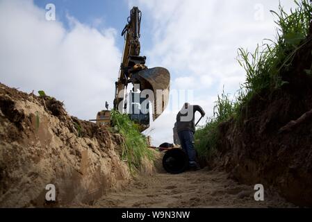 Installation einer Sturmabfluß und Ablaufleitung neben einer landwirtschaftlichen Straße läuft Stockfoto