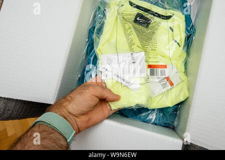 Paris, Frankreich, 28.Juni, 2019: der Mensch hand unboxing neue Nike Running Kleidung an der Nike Schriftzug und Standard Fit-Tag auf der Suche nach t-shirt Stockfoto