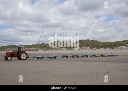 Eine Tractor Pulling 9 verknüpft sand Yachten, ohne Segel, auf den Strand in Vorbereitung für einen Wettbewerb Stockfoto