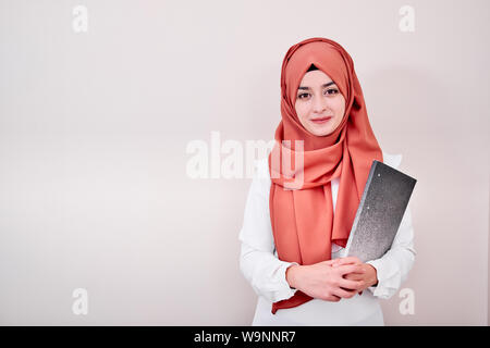 Junge muslimische Mädchen schauen in die Kamera und halten Datei Ordner, zurück in die Schule oder Ausbildung Konzept Foto Stockfoto