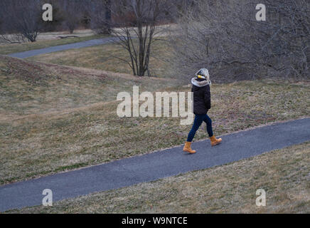 Junge Frau in kaltem Wetter Gang bei einem Spaziergang im Park trotz der Gefrierpunkt. Stockfoto