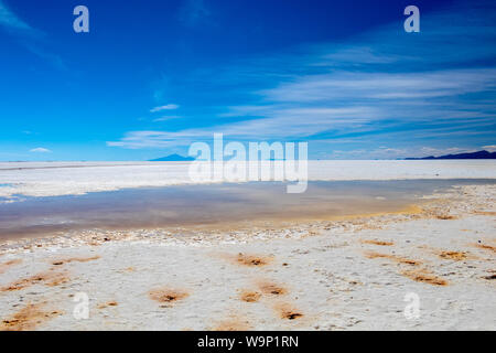 Landschaft von unglaublich weißen Salzsee Salar de Uyuni, inmitten der Anden im Südwesten von Bolivien, dem größten Salzsee Szene der Welt mit blauem Himmel in Sunn Stockfoto