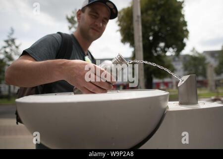 Berlin, Deutschland. 12 Aug, 2019. Ein Passant füllt seine Trinkflasche mit Wasser bei einer Berliner Wasserbetriebe Brunnen, eine sogenannte "Fill Station'. Es ist nahezu überall verfügbar, Kosten kaum etwas und die Qualität stimmt. Aus der Sicht des Umweltministers, Leitungswasser ist das Mittel der Wahl gegen Durst - auch mit Blick auf den Klimaschutz. (Auf dpa' für Klima und Umwelt: Die Bundesregierung fördert Leitungswasser als Durstlöscher 'Credit): Jörg Carstensen/dpa/Alamy leben Nachrichten Stockfoto