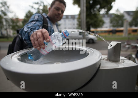 Berlin, Deutschland. 12 Aug, 2019. Ein Passant füllt seine Trinkflasche mit Wasser bei einer Berliner Wasserbetriebe Brunnen, eine sogenannte "Fill Station'. Es ist nahezu überall verfügbar, Kosten kaum etwas und die Qualität stimmt. Aus der Sicht des Umweltministers, Leitungswasser ist das Mittel der Wahl gegen Durst - auch mit Blick auf den Klimaschutz. (Auf dpa' für Klima und Umwelt: Die Bundesregierung fördert Leitungswasser als Durstlöscher 'Credit): Jörg Carstensen/dpa/Alamy leben Nachrichten Stockfoto