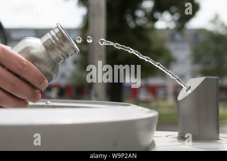 Berlin, Deutschland. 12 Aug, 2019. Ein Passant füllt seine Trinkflasche mit Wasser bei einer Berliner Wasserbetriebe Brunnen, eine sogenannte "Fill Station'. Es ist nahezu überall verfügbar, Kosten kaum etwas und die Qualität stimmt. Aus der Sicht des Umweltministers, Leitungswasser ist das Mittel der Wahl gegen Durst - auch mit Blick auf den Klimaschutz. (Auf dpa' für Klima und Umwelt: Die Bundesregierung fördert Leitungswasser als Durstlöscher 'Credit): Jörg Carstensen/dpa/Alamy leben Nachrichten Stockfoto