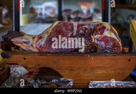 Ganzen Schinken mit Knochen Bein des montenegrinischen Njeguski prsut Schinken ähnlich wie Schinken und geschnittenes verpacktes Fleisch auf dem Markt in Kotor, Montenegro Stockfoto