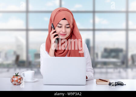 Hijab muslimische Frau die Arbeit mit Computer und muslimischen Mädchen am Telefon sprechen Stockfoto