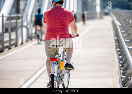 Ein älterer Mann Radfahrer Pedale ein Fahrrad und Fahrten entlang der Tilikum Crossing Bridge, sondern wie die meisten Portland Bewohner eine Aktiv gesund Lifestyl Stockfoto