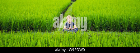 Kleiner Junge übt Yoga in einem Reisfeld, Outdoor. Gymnastische Übungen, Banner, LANGE FORMAT Stockfoto