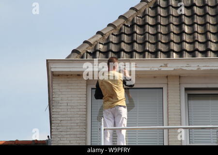 Ein Maler bei der Arbeit auf dem Gerüst Stockfoto