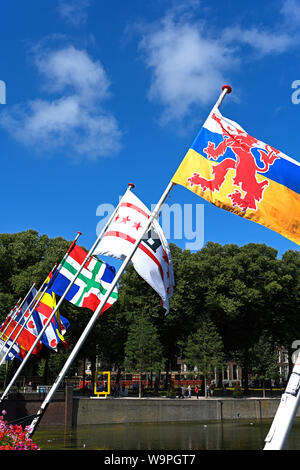 Den Haag, Niederlande - 2019.08.07: Flaggen der niederländischen Provinzen an hofvijver/buitenhof in der Nähe von binnenhof, Hintergrund Menschen zu Lange Vijverberg Stockfoto