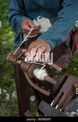 Handwerker mit einem alten Spinnrad wolle in Garn zu drehen. Stockfoto