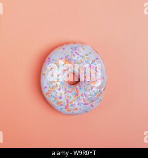 Köstliche Krapfen mit weißer Glasur und bunten Streuseln auf pastellfarbenen Hintergrund Stockfoto