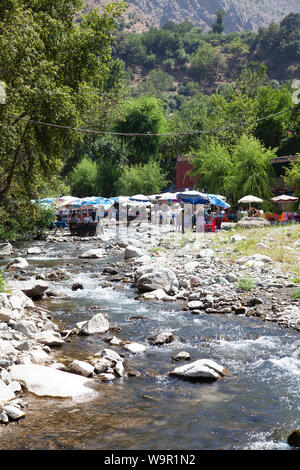 Die Leute sitzen in den Restaurants am Fluss bei Sti Fadma, Ourika Tal in den Atlas, Marokko Stockfoto