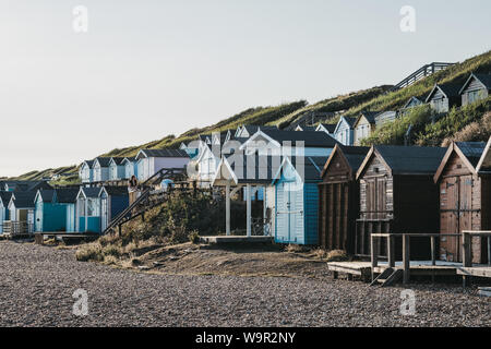 Milford on Sea, Großbritannien - 13 Juli 2019: Menschen entspannend durch die bunten Badekabinen in Milford on Sea, einem traditionellen englischen Dorf, das bekannt ist für breathtak Stockfoto