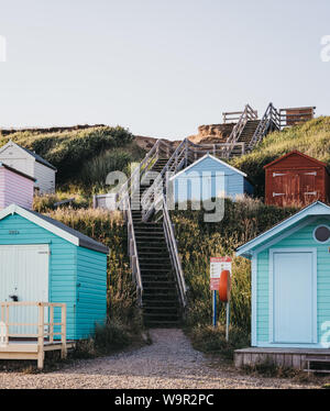 Milford on Sea, Großbritannien - 13 Juli 2019: Treppe zum Strand zwischen bunten Badekabinen in Milford on Sea, einem traditionellen englischen Dorf, das bekannt ist für breat Stockfoto