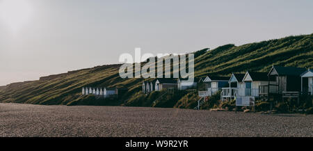 Panoramablick auf Strand Hütten bei Sonnenuntergang in Milford on Sea, Hampshire, UK. Stockfoto