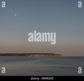 Blick auf die Nadeln auf der Isle of Wight vom Milford on Sea, New Forest, UK, auf einem klaren, warmen Sommerabend, Mond am Himmel. Stockfoto