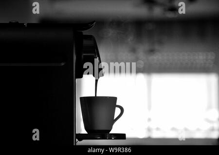 Espressomaschine in Silhouette, füllen Sie eine Tasse Kaffee mit Licht Dampf. Stockfoto