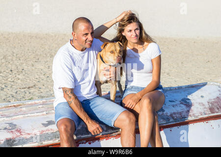 Junge Erwachsene Paar mit Hund einen entspannenden Spaziergang am Sandstrand Stockfoto