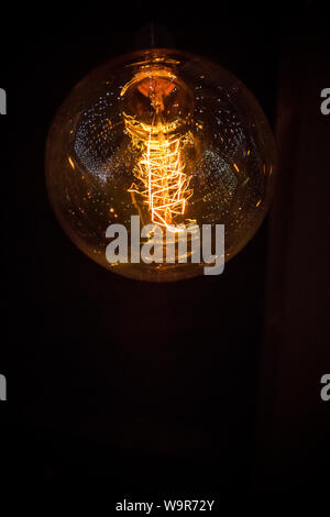 Eine Nahaufnahme einer Glühbirne in der Dunkelheit mit dekorativen Leuchten in Es widerspiegelt Stockfoto