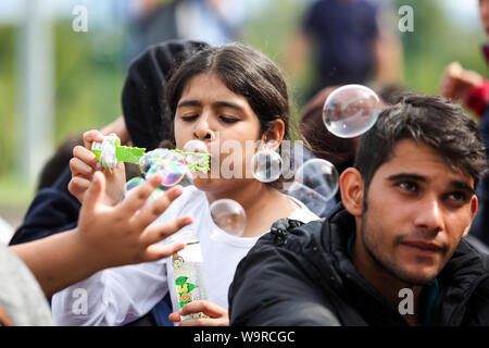 Bregana, Slowenien - 20. September 2015: Eine syrische Flüchtlinge Mädchen blasen blasen Auf der slowenischen Grenze mit Kroatien. Die Migranten warten. Stockfoto