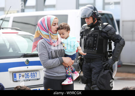 Bregana, Slowenien - 20. September 2015: Eine junge syrische Frauen mit einem Kind zu Fuß neben ein Polizist auf der slowenischen Grenze mit Kroatien. Stockfoto