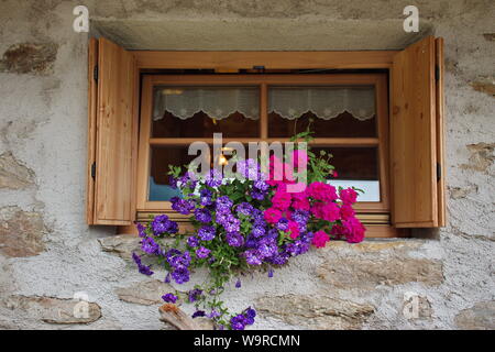 Fenster des Hauses aus Stein geschmückt mit Blumen Stockfoto