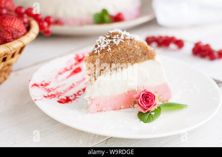 Zarte keine bake Strawberry cheesecake Slice auf weißen Teller dekoriert Rosebud Stockfoto