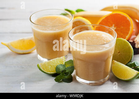 Frisch gemischt, Bananen und Zitrusfrüchte Smoothie oder Milchshake in zwei Gläser mit rohen Zutaten. Frische Vitamine, selbstgemachte erfrischende Frucht trinken Stockfoto