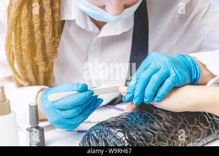 Frau Maniküre Master macht gel Beschichtung Lack im Salon. Das Konzept der Schönheit Professionelle Nagelpflege Stockfoto