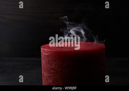 Red erloschen Kerze mit Rauch trailing aus den Docht auf dunklem Hintergrund Stockfoto