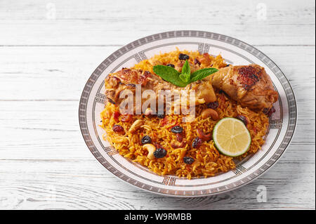 Huhn oder Chicken biryani Kabsa am weißen Holz- Hintergrund. Kabsa ist traditionell saudi-arabische Küche Teller. Kabsa kocht mit Basmati Reis, Huhn, Stockfoto