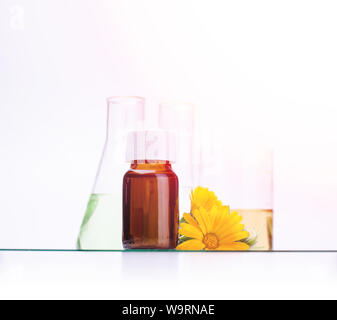 Dunkle kosmetische Flasche aromatisches Öl für pflanzliche Arzneimittel mit Calendula flower auf weißen Hintergrund isoliert. Ringelblumen Extrakt. Stockfoto
