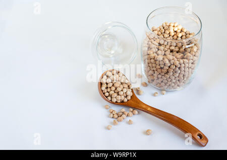 Kichererbsen in einem Glas mit einem Löffel aus Holz auf einem rosa Hintergrund Kopie Raum Text Stockfoto