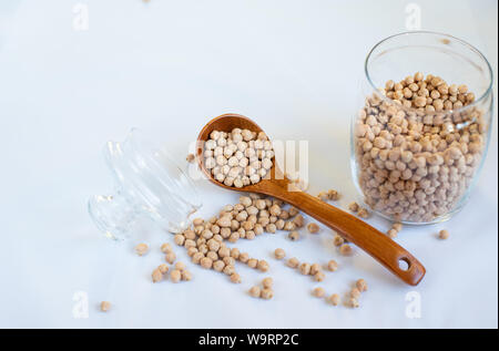 Kichererbsen in einem Glas mit einem Löffel aus Holz auf einem rosa Hintergrund Kopie Raum Text Stockfoto