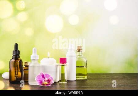 Komposition mit viel unterschiedlicher Größe, Form und Material Beauty Kosmetik Produkte Flaschen Anordnung auf hölzernen Tisch mit grünen bokeh Studio hinterg Stockfoto