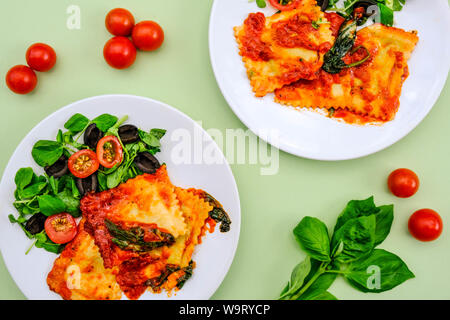 Im italienischen Stil Spinat und Ricotta gefüllte Ravioli Essen mit schwarzen Oliven anda Grüner Salat Stockfoto
