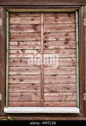 Sehr alte Fenster mit Fensterläden aus Holz. Ungepflegte primitive Fenster. Stockfoto